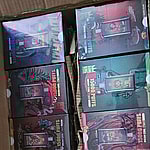 A box filled with multiple colorful packages of disposable vape devices labeled "15000 PUFFS Mesh Coil."