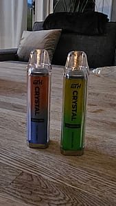 Två färgglada ETH Crystal vape-enheter på ett träbord.