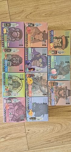 Nine boxes of vape products, each featuring colorful packaging with various gorilla illustrations wearing different outfits and accessories. The boxes are arranged in a grid on a wooden floor.