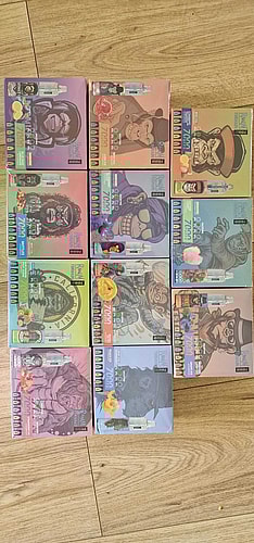 Nine boxes of vape products, each featuring colorful packaging with various gorilla illustrations wearing different outfits and accessories. The boxes are arranged in a grid on a wooden floor.