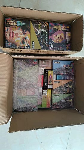 A cardboard box containing various vape products, with colorful packaging visible inside.