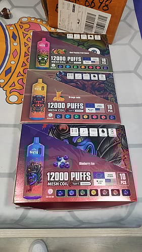 Three boxes of Bang XXL disposable vapes, each offering 12,000 puffs with mesh coils, featuring different flavors: Kiwi Passion Fruit Guava, Orange Soda, and Blueberry Ice.