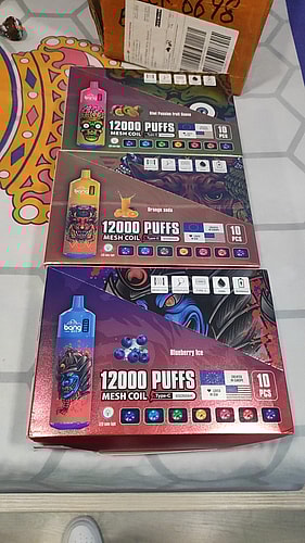 Three boxes of Bang XXL disposable vapes, each offering 12,000 puffs with mesh coils, featuring different flavors: Kiwi Passion Fruit Guava, Orange Soda, and Blueberry Ice.