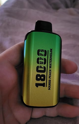 A hand holding a green and yellow gradient vape device with "18000" and additional text printed on it.