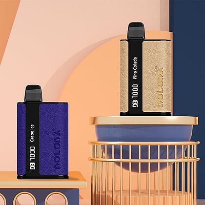 Dos dispositivos de vapeo en forma de caja etiquetados como "DOLODA D3 1000" con sabores "Grape Ice" y "Piña Colada" se muestran en una disposición geométrica de bloques y cilindros de colores pastel.