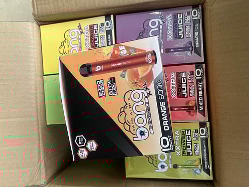 A box of assorted Bang XXL disposable vape pens, with visible flavors including Orange Soda, Grape Ice, Mixed Berry, and Honeydew Melon Ice.