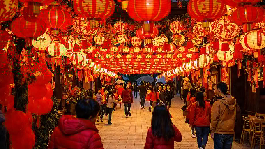 Una calle vibrante decorada con faroles rojos y adornos festivos, llena de gente disfrutando de una celebración.