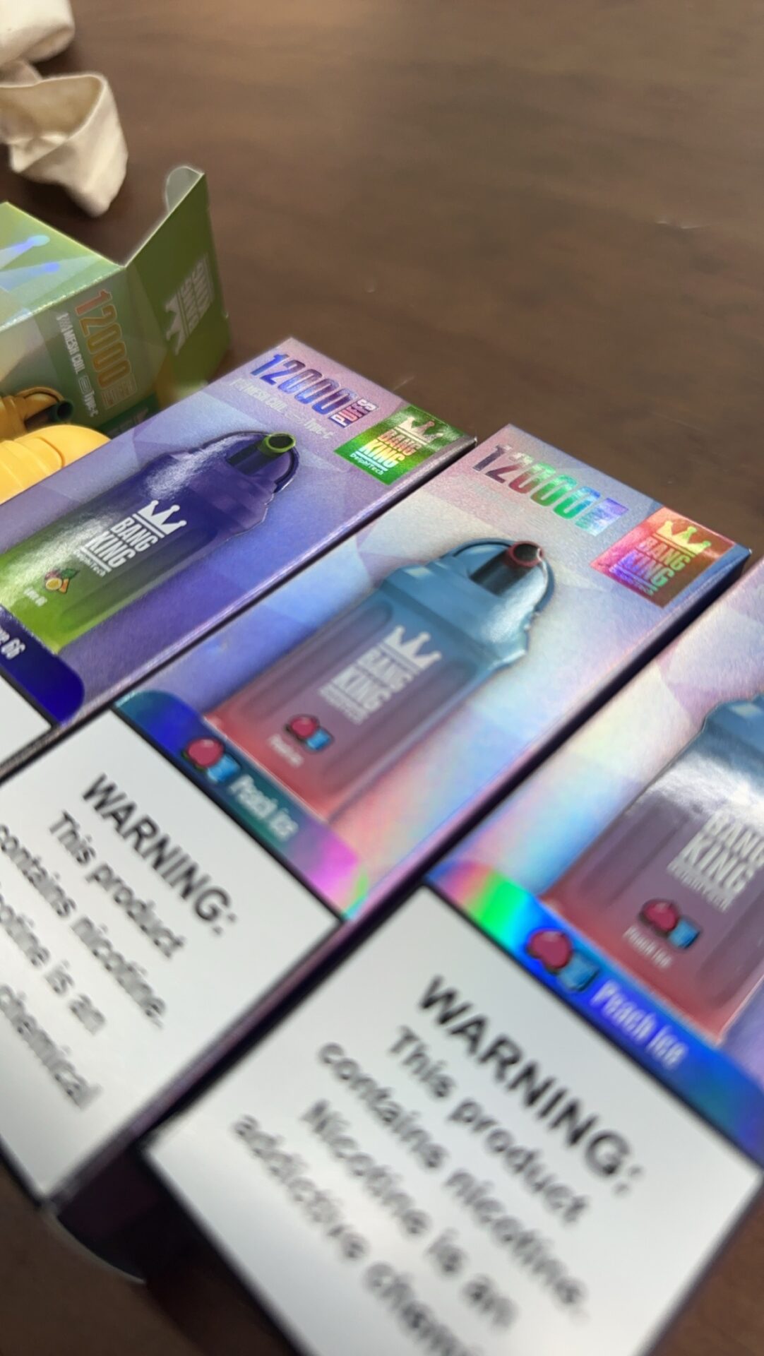 Three boxes of Bang King vapes with 12,000 puffs each, featuring colorful packaging and nicotine warning labels at the bottom.