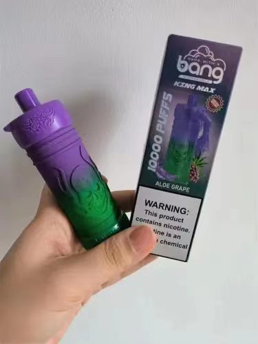 A person holding a purple and green vape device next to its packaging labeled "bang KZNG MAX Aloe Grape" with a warning that the product contains nicotine.