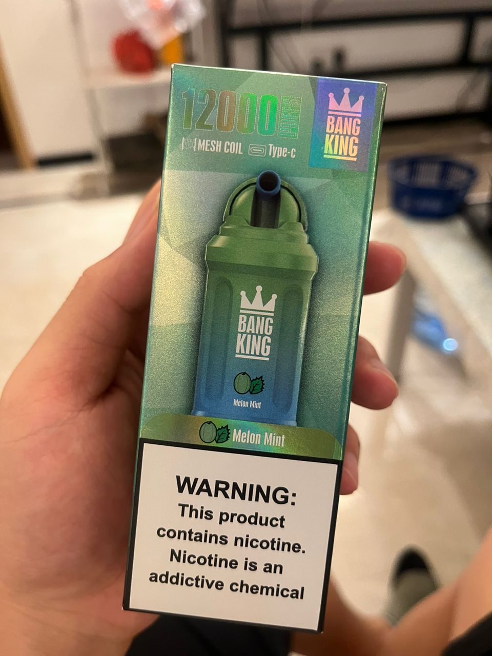 A box of Bang King vape with 12000 puffs, mesh coil, Type-C charging, and melon mint flavor, displaying a nicotine warning label.