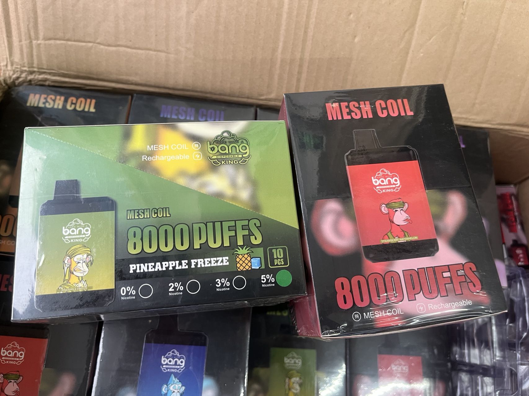 Boxes of Bang King vape products featuring mesh coil devices with 8000 puffs, available in Pineapple Freeze and Strawberry Watermelon flavors, displayed in a cardboard box.