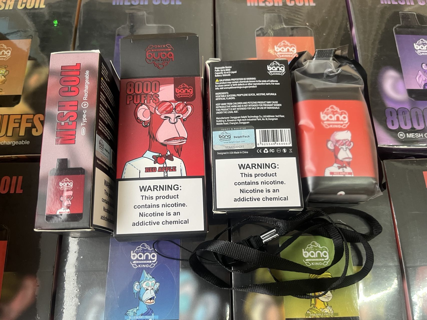 Boxes of Bang King disposable vapes with "8000 PUFFS" and "Red Apple" flavor are displayed, featuring a cartoon monkey wearing a tie and glasses. The warning label states: "This product contains nicotine. Nicotine is an addictive chemical."