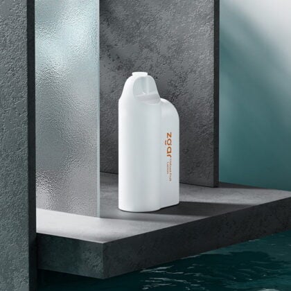 Weiße, minimalistische Wasserflasche mit modernem Design, die auf einem Betonpodest neben strukturiertem Glas und Wasser steht.