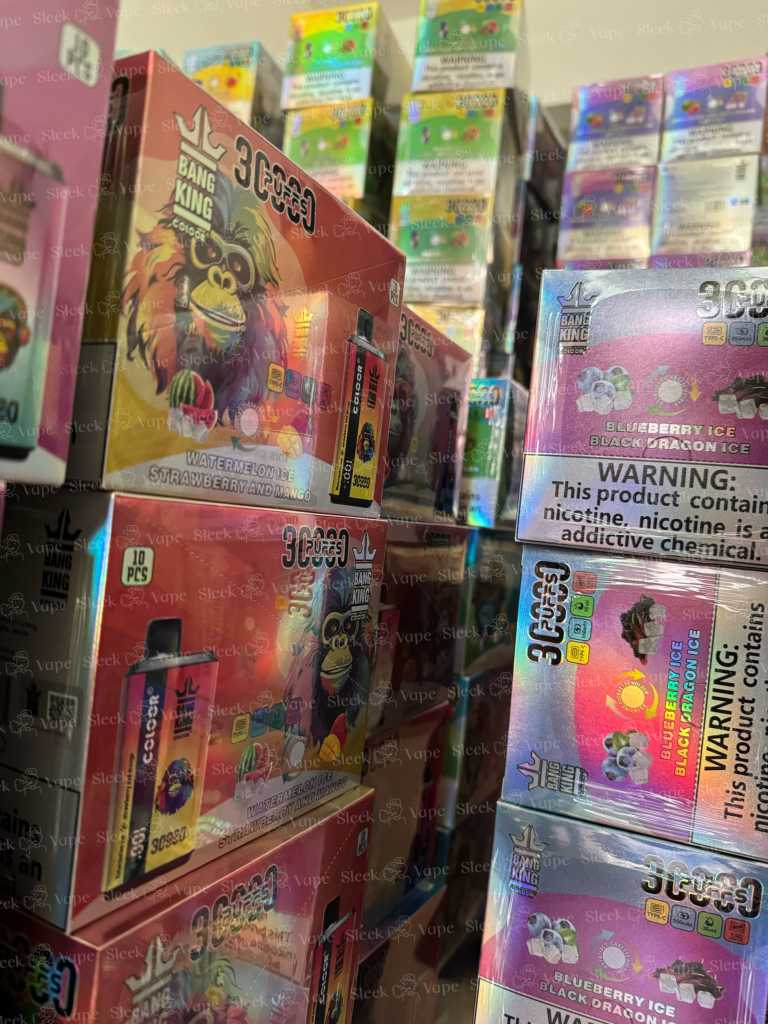 A display of various flavored vape products with colorful packaging, prominently featuring warning labels about nicotine content.