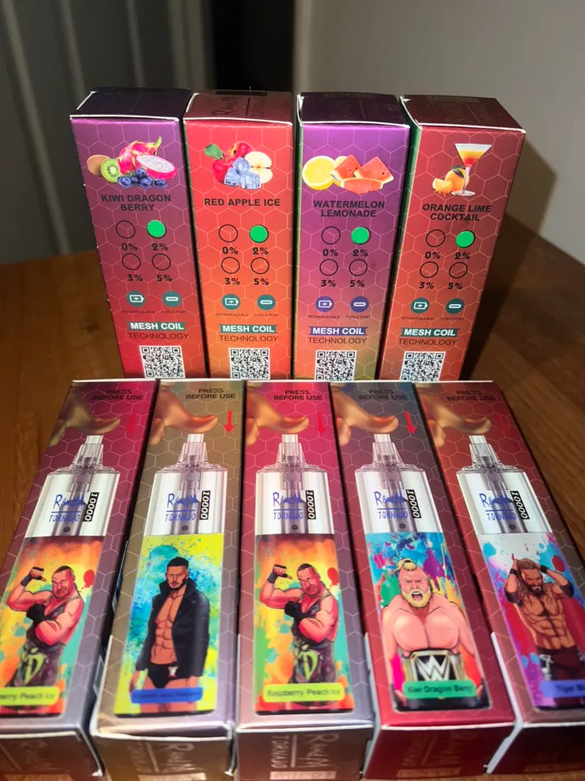 Four boxed vape products with different flavors are displayed, including Kiwi Dragon Berry, Red Apple Ice, Watermelon Lemonade, and Orange Lime Cocktail. The boxes have colorful illustrations of the flavors and images of wrestlers on the vape devices.