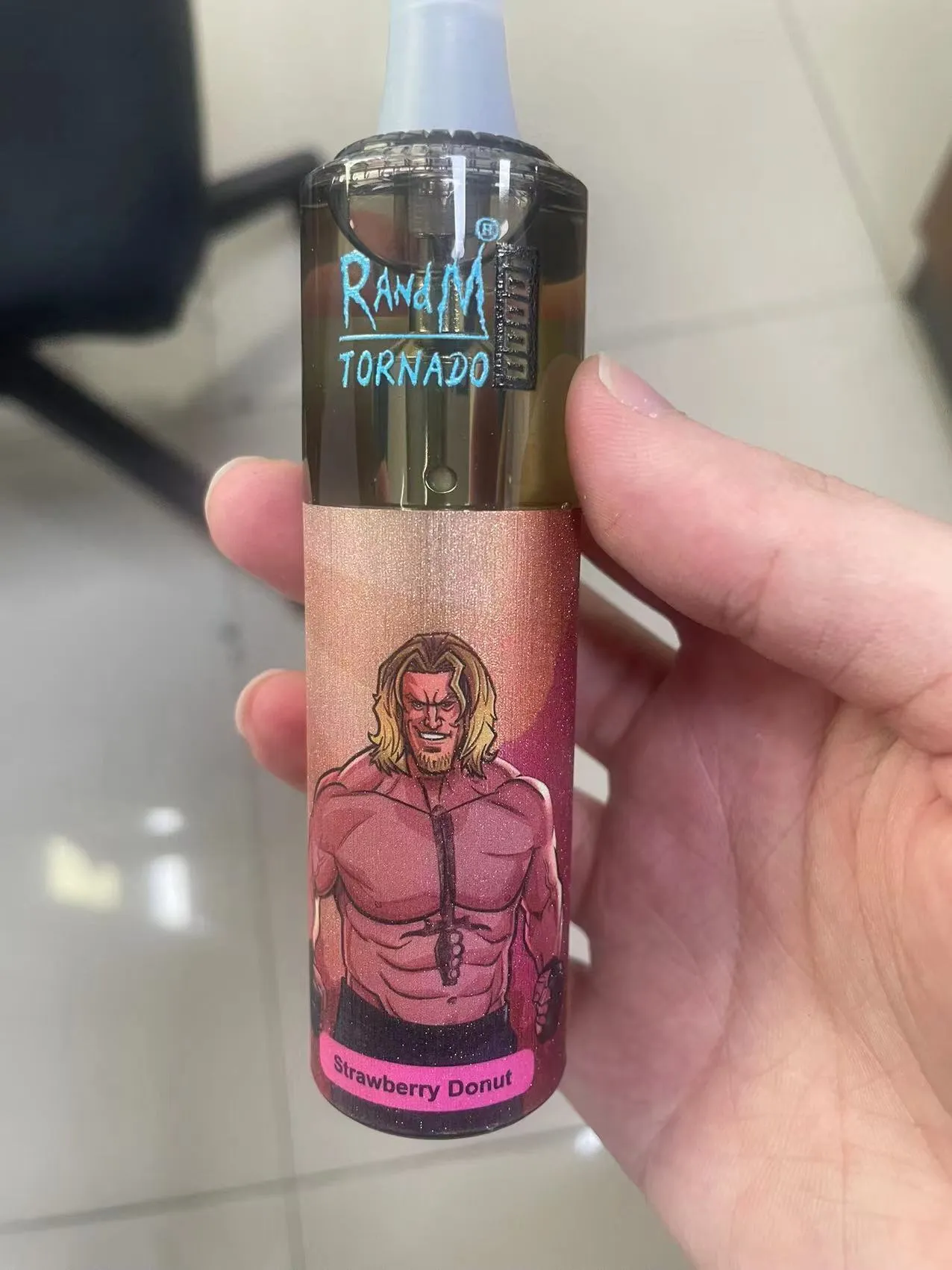 A hand holding a vape device labeled "RandM Tornado" with a "Strawberry Donut" flavor, featuring an illustration of a muscular man with long blonde hair.