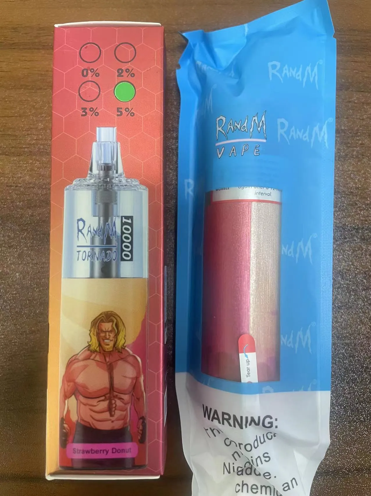 Packaging of a RandM Tornado vape device with a strawberry donut flavor, showing 2% nicotine strength and featuring a muscular cartoon character on the box.