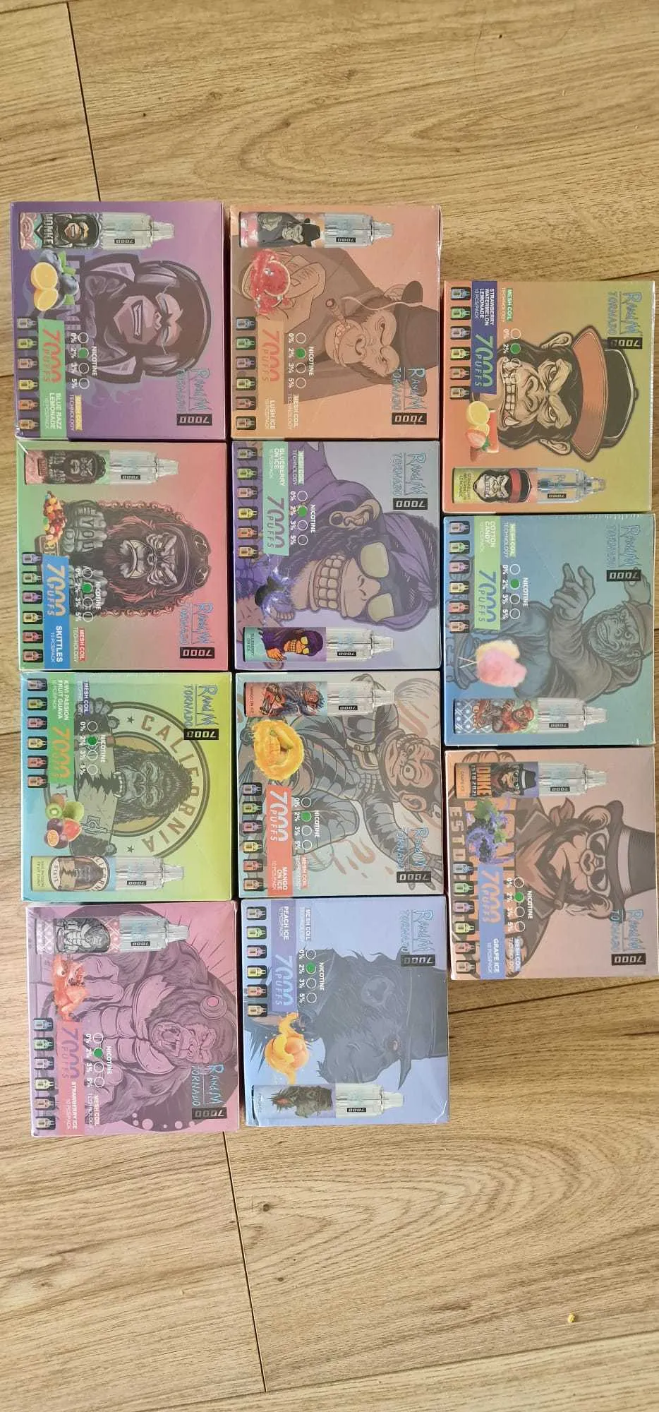 Nine boxes of vape products, each featuring colorful packaging with various gorilla illustrations wearing different outfits and accessories. The boxes are arranged in a grid on a wooden floor.