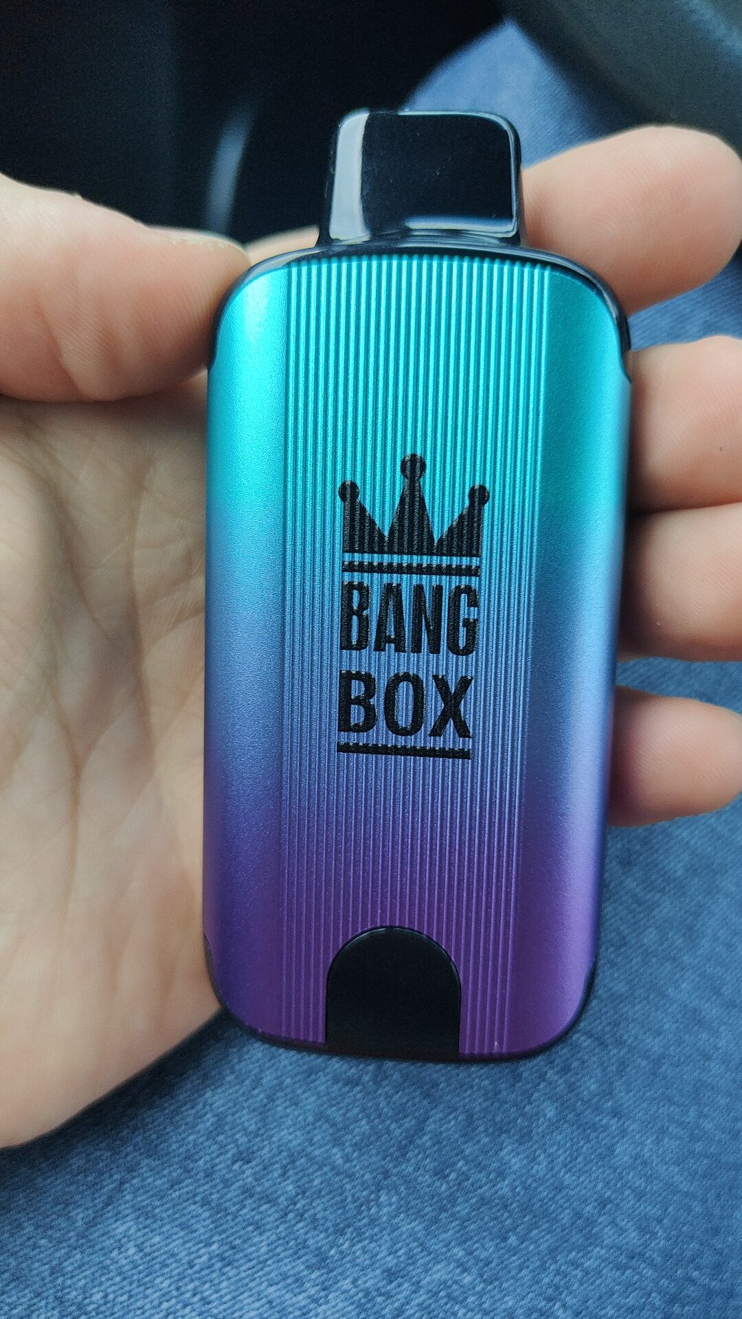 A hand holding a small metallic device labeled "BANG BOX" with a crown icon on the front.