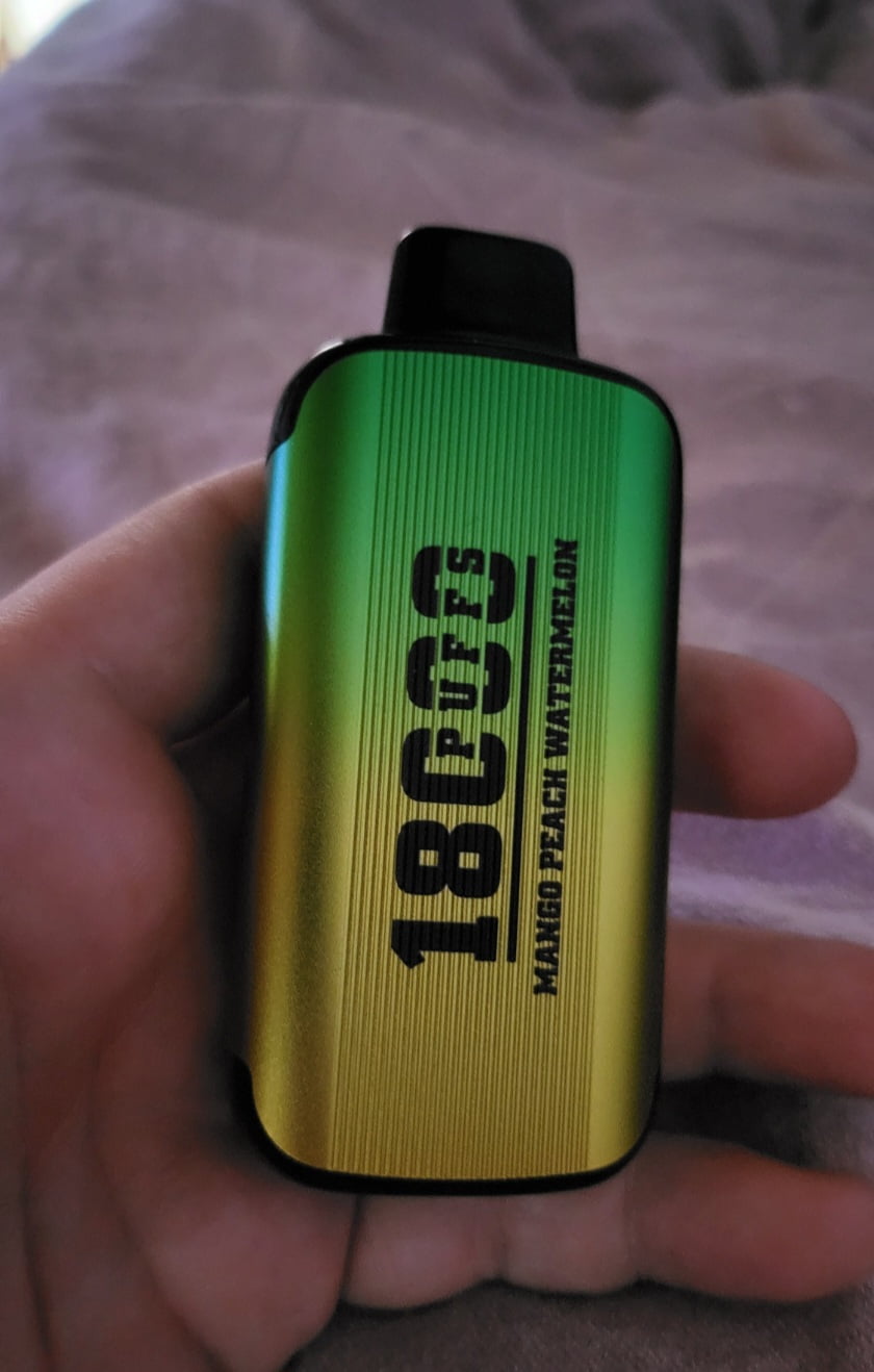 A hand holding a green and yellow gradient vape device with "18000" and additional text printed on it.