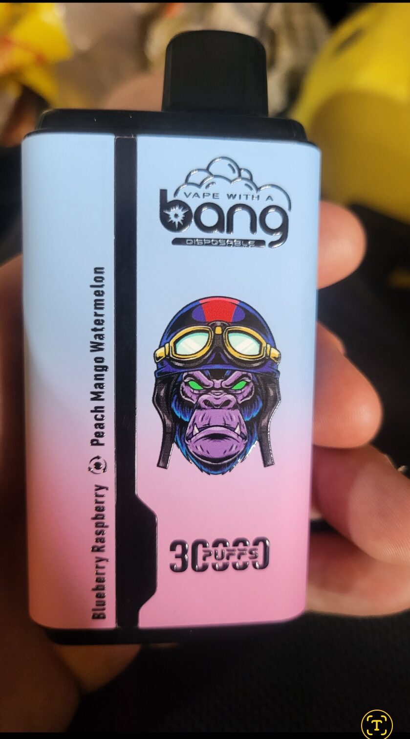 A close-up of a disposable vape device with a design featuring a purple gorilla wearing goggles. The text "Vape with a Bang" is visible at the top, and flavors like "Blueberry Raspberry" and "Peach Mango Watermelon" are listed. The device also indicates "3000 Puffs" at the bottom.