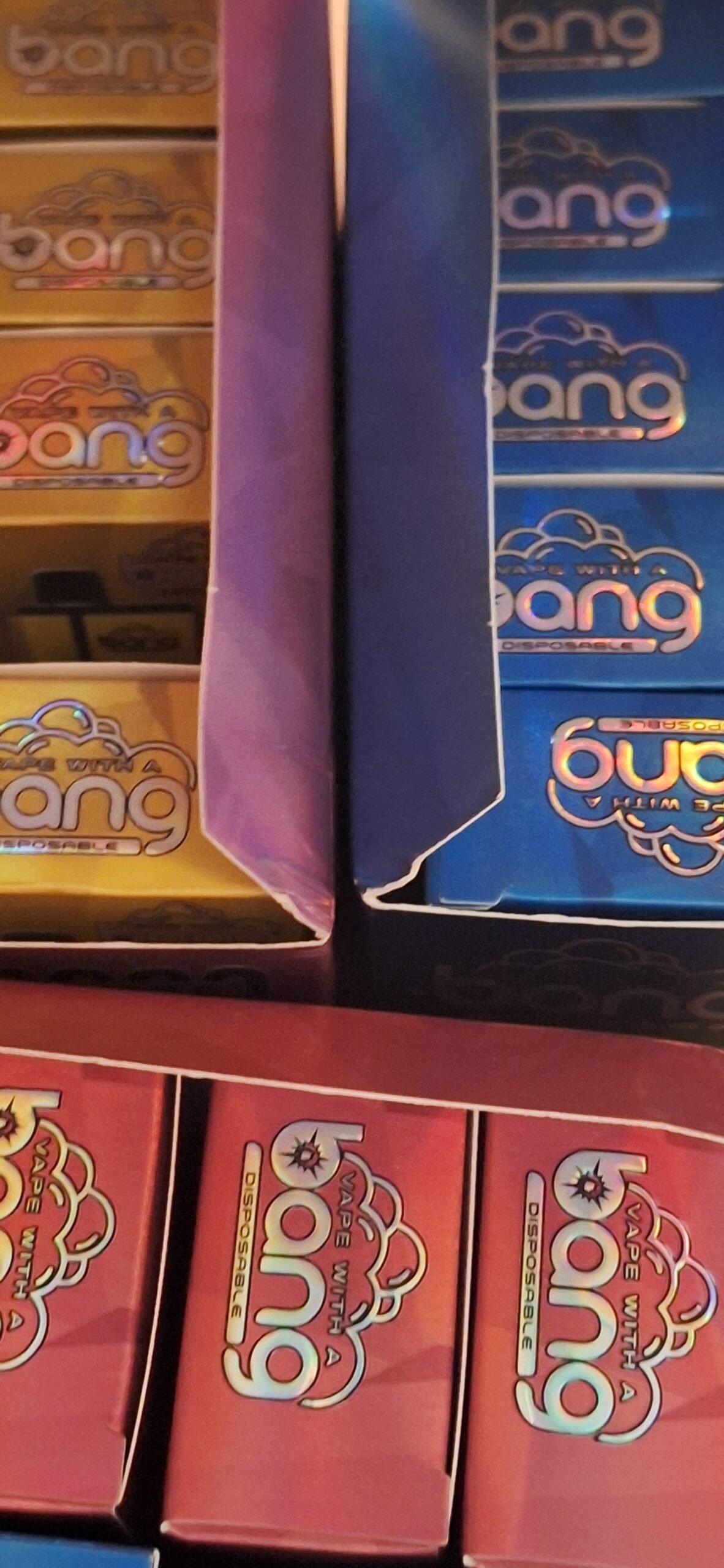 Boxes of disposable vape products with "bang" branding in various colors, including yellow, blue, and red.